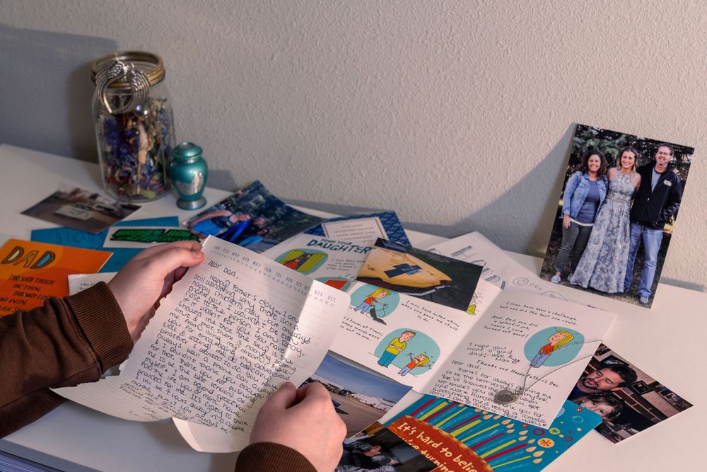 Person reading handwritten notes with photographs and memorabilia displayed on a desk.
