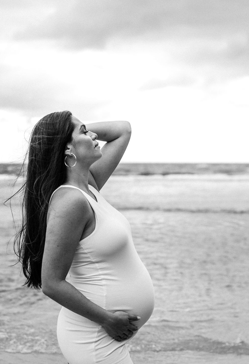 Black and white artistic maternity portraits against ocean backdrop.