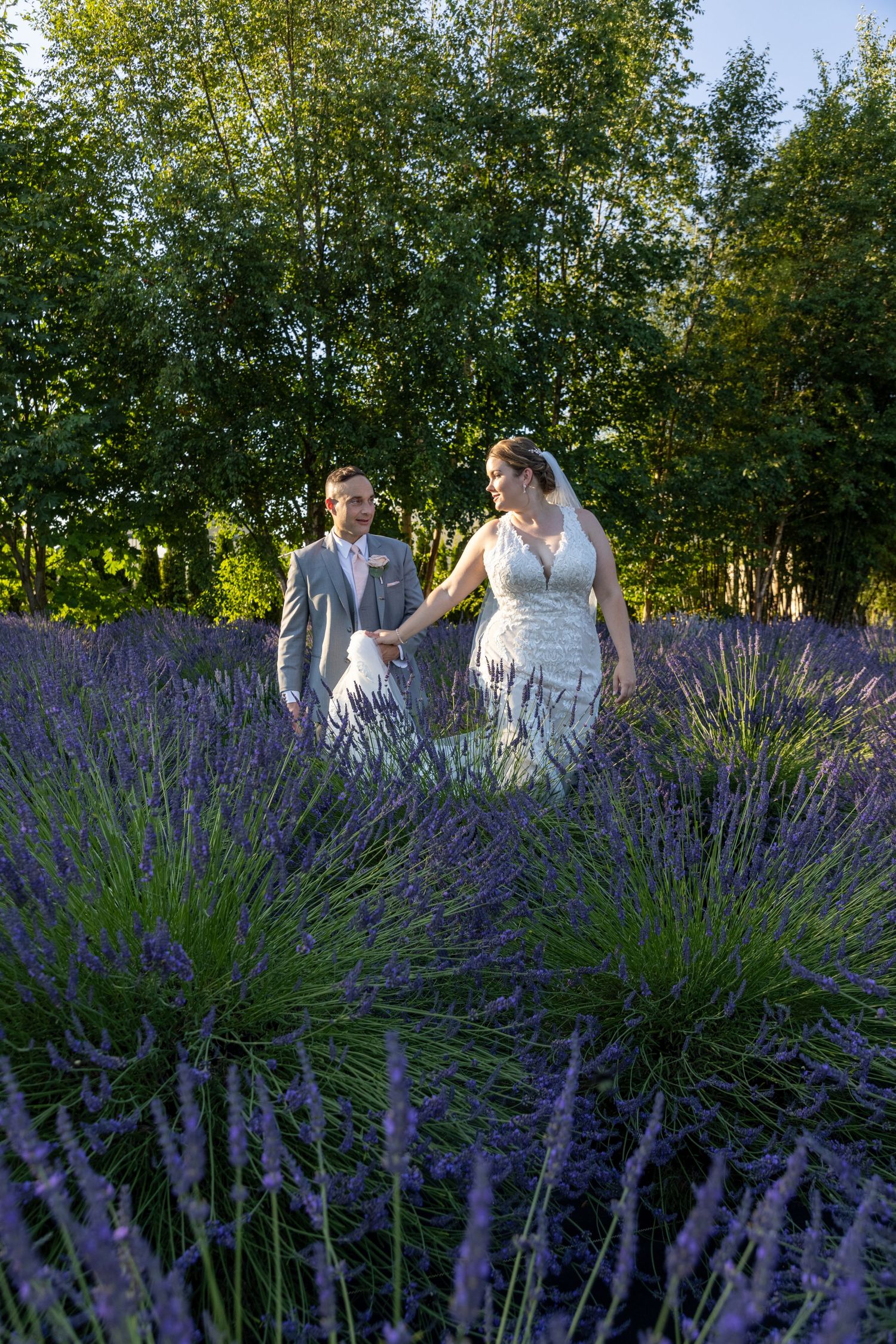Newlyweds share joyful moment while standing in beautiful lavender field.