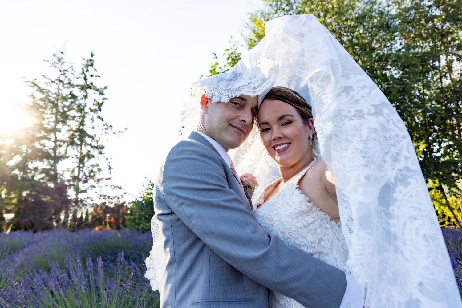 Wedding couple embraces in blooming lavender field during golden hour.