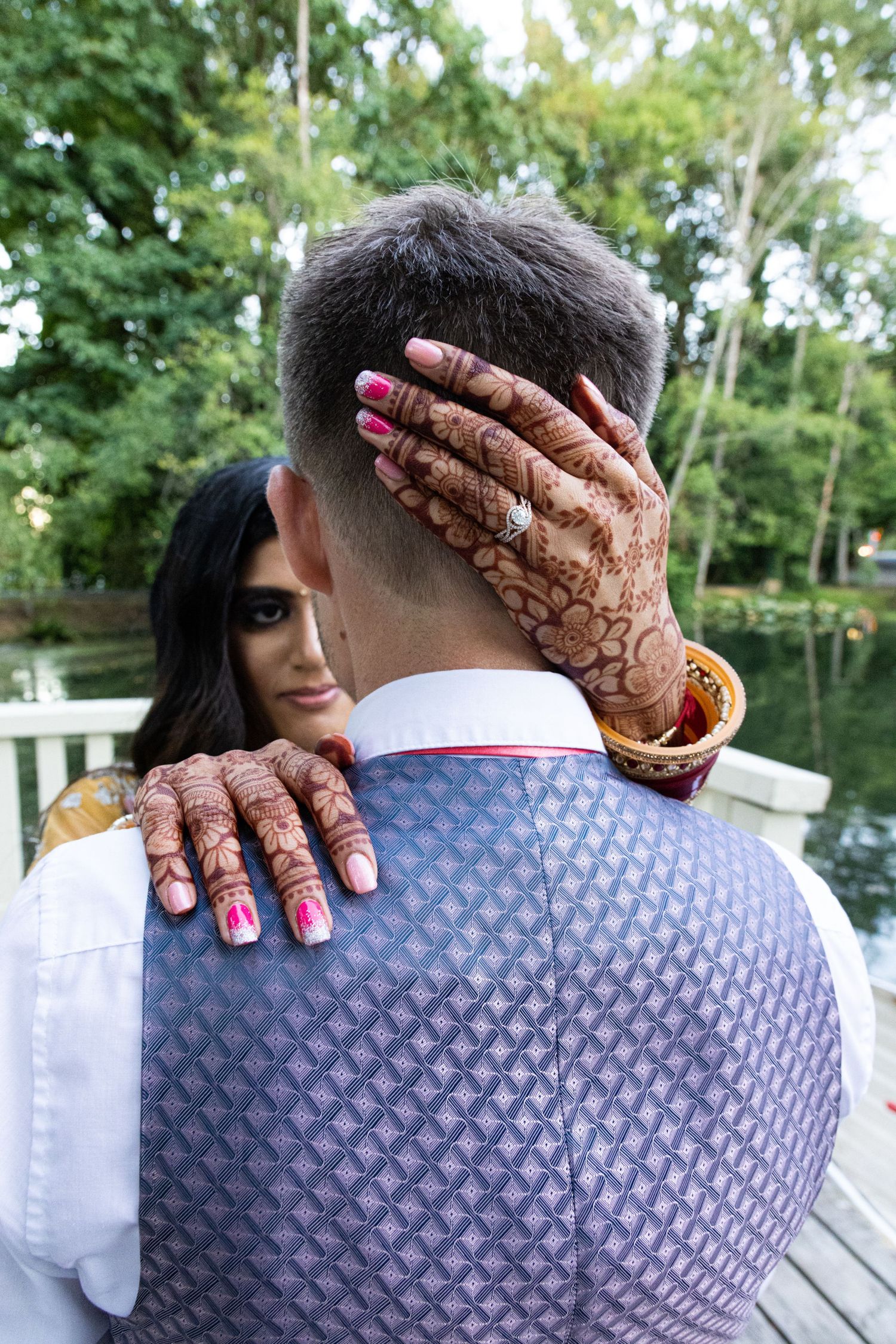 Close view of decorated hands with henna embracing on wooden deck.