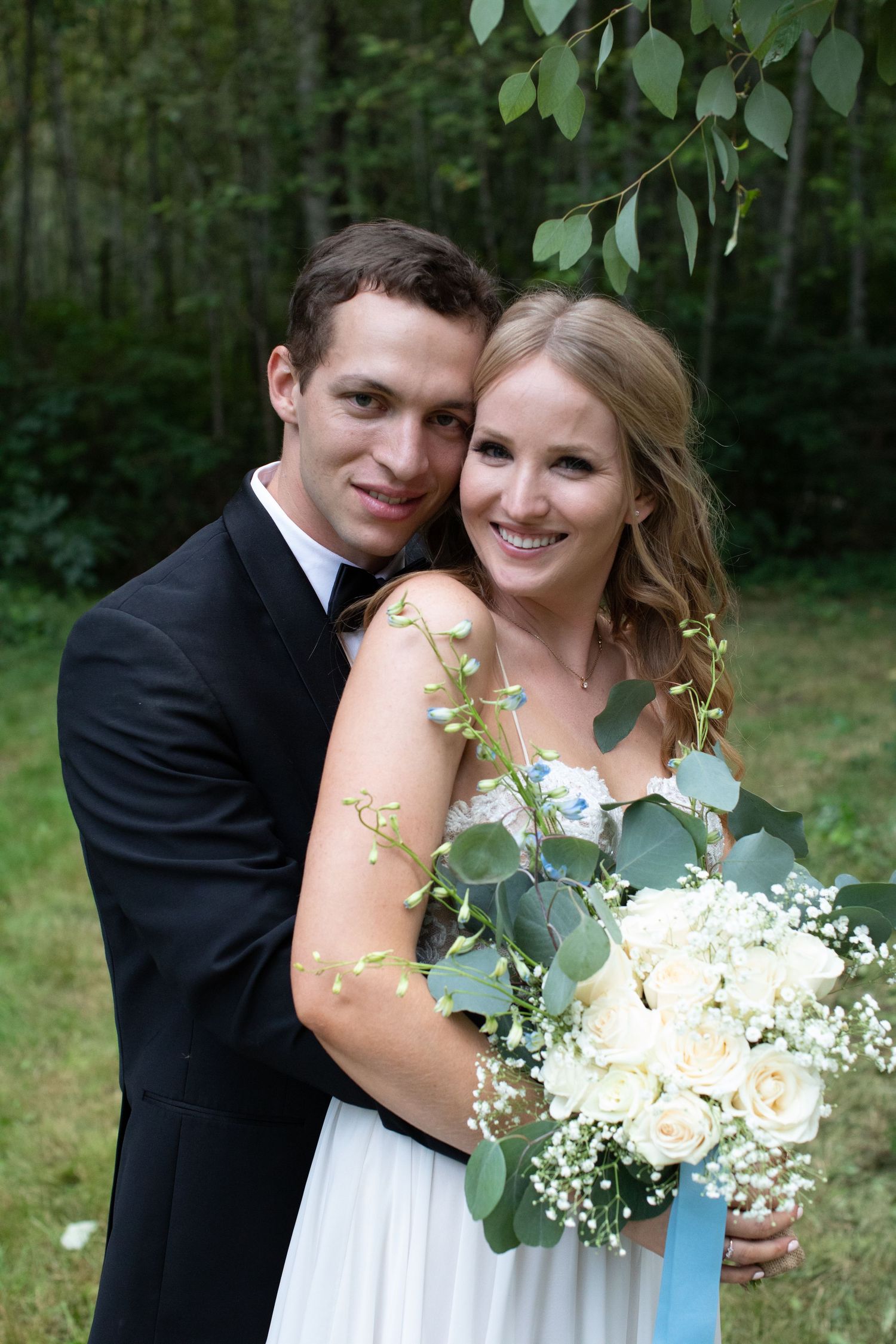 A romantic wedding portrait of a couple with the bride holding a white and green bouquet.