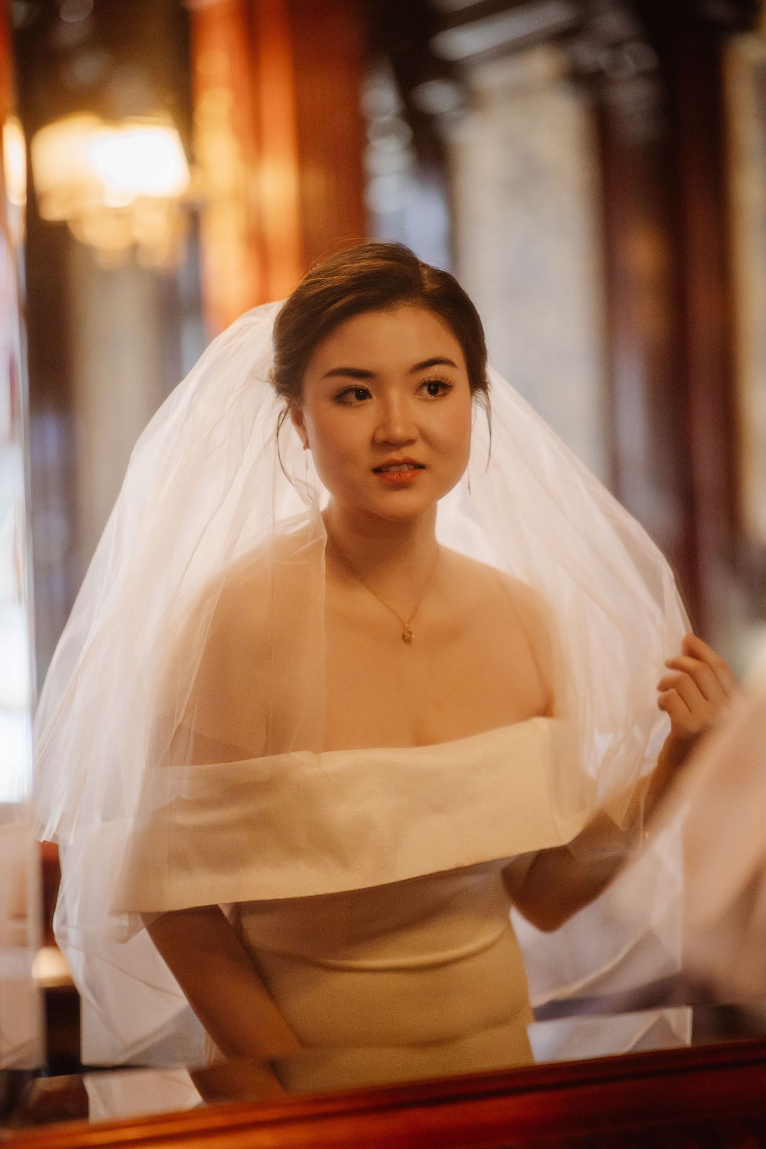 Bride in classic white gown and veil in elegant vintage setting.
