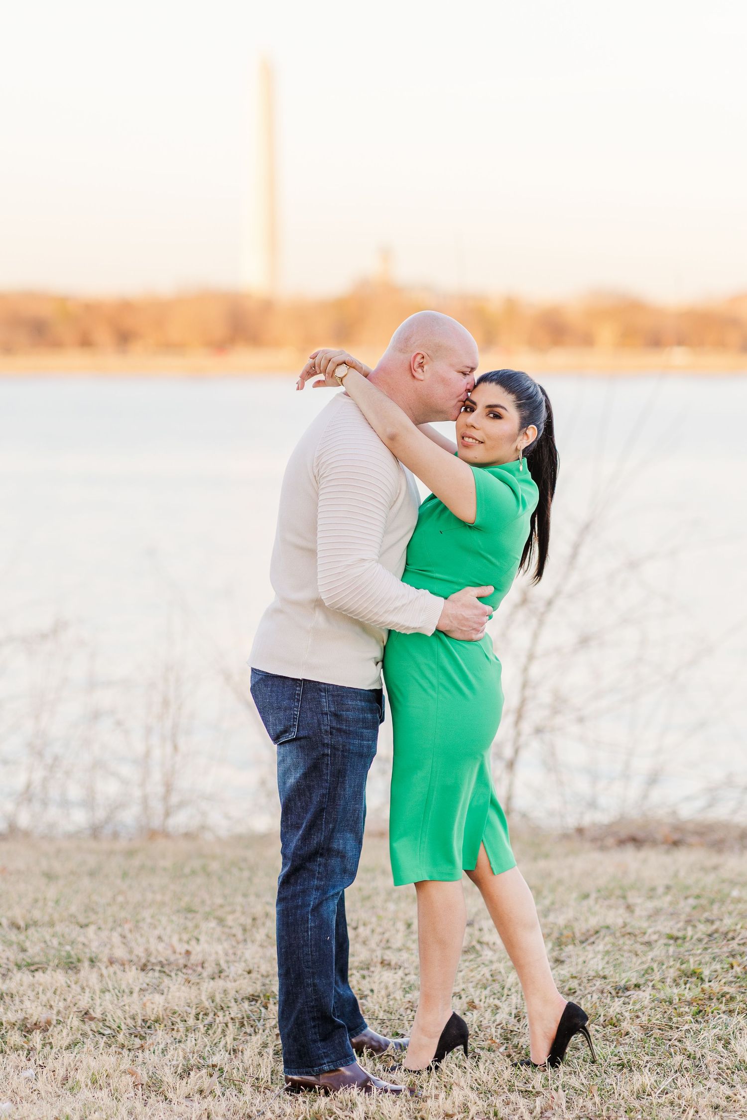 Couple dancing together in field with Washington Monument visible in background.
