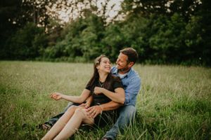 Couple relaxing together in a sunny meadow during golden hour.