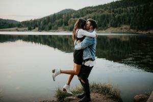 Romantic lakeside photoshoot with mountain views and natural scenery at sunset.