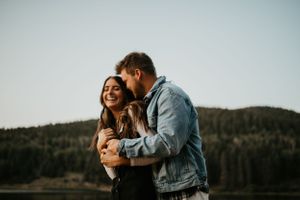 Intimate outdoor couples photography session with mountain lake backdrop at dusk.
