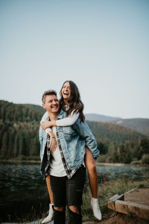 Playful couple shares joyful moments by a serene mountain lake.