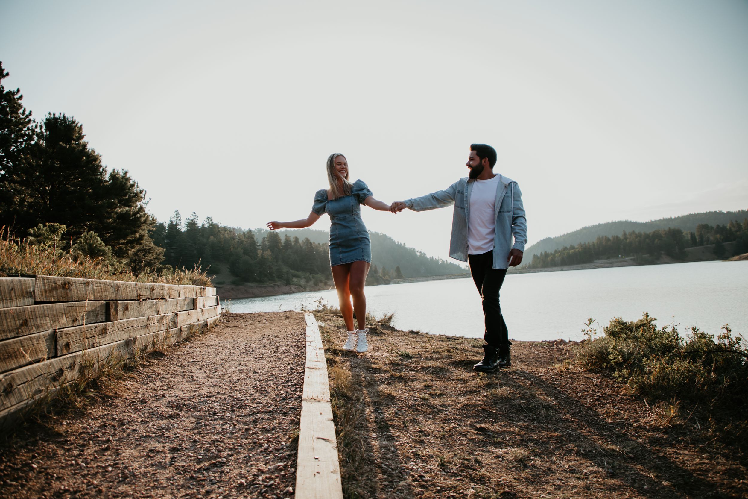 Romantic couple poses together on scenic coastal path during golden hour photography session.