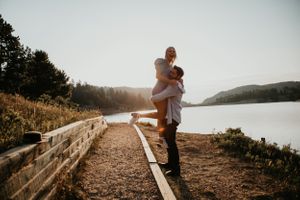 Couple embraces in romantic sunset photoshoot along scenic coastal cliffside path.