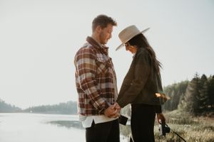 Couple shares intimate moment during outdoor photoshoot with mountain backdrop.