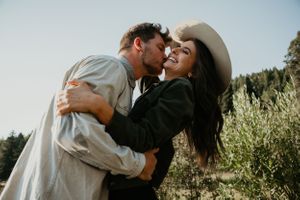 Romantic couple embraces during sunset photoshoot in natural outdoor setting.