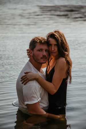 A romantic couple sharing an intimate moment in the water at dusk.