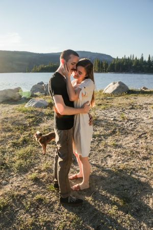 Couple shares intimate moments by a scenic mountain lake during golden hour.