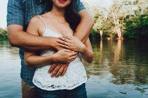 Couple in casual summer attire sharing intimate moments by a lake.