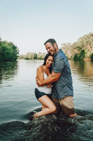 Couple playing and splashing together in a scenic lake during a romantic photoshoot.