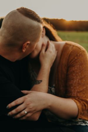 A romantic couple embraces in golden sunlight wearing rustic fall clothing during an intimate photoshoot.