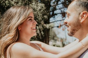 A couple shares laughter and intimate moments during a sunny outdoor portrait session.