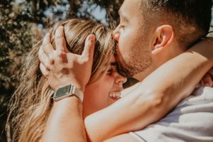 An intimate close-up of a couple embracing during a sunny outdoor photoshoot.