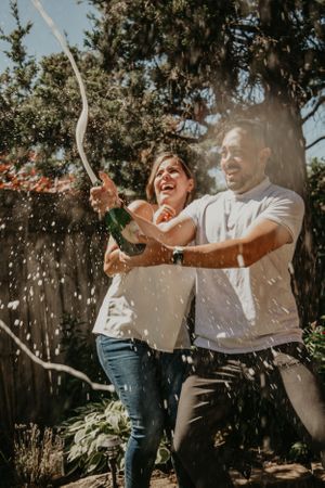 A joyful couple playfully throwing confetti in a backyard garden setting.