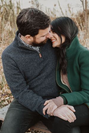 A couple sharing intimate moments outdoors in winter wearing cozy sweaters.