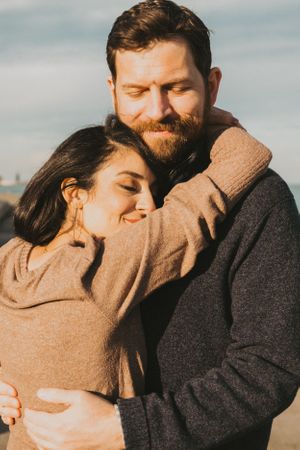 Tender moments captured between a couple in warm sweaters during golden hour.