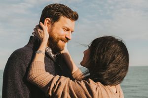 A romantic couple embracing by the ocean on a sunny afternoon.