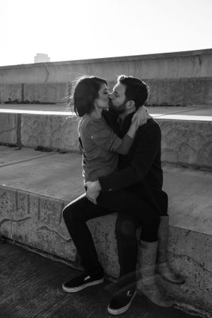 Black and white romantic photos of a couple sitting on concrete steps.