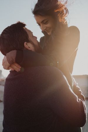 Romantic sunset photoshoot with couple embracing in warm backlight.