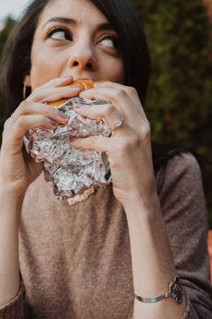 Person taking bites of food wrapped in foil in a sequence of casual photos.