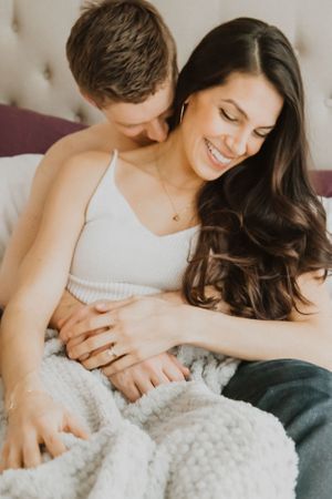 Intimate portrait of couple relaxing together under cozy white blanket.