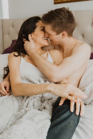 Couple sharing playful intimate moments while lounging in bed.