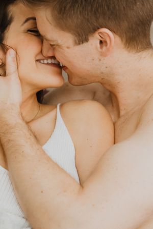 Close-up of couple sharing intimate moment against light background.