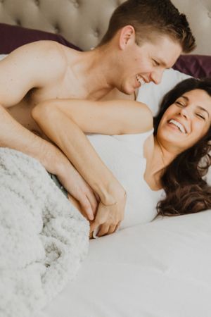 Romantic couple sharing affectionate moments while resting on plush bedding.
