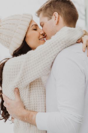 A couple in cozy winter wear shares romantic moments against a white background.