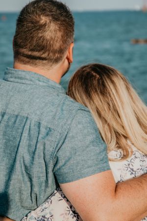 A couple in casual attire shares an intimate moment by the seaside.