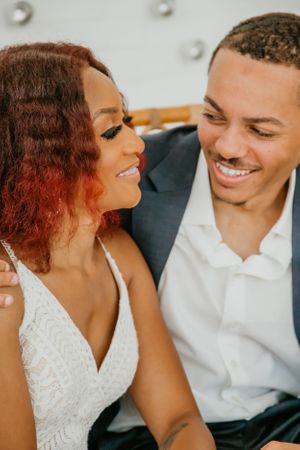 Couple in formal wedding attire sharing joyful laughter during an intimate moment.