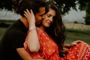 Intimate couple embracing on grass in a romantic outdoor setting.
