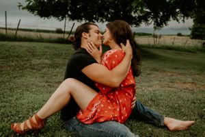 Couple sharing tender moments while sitting in a grassy field.