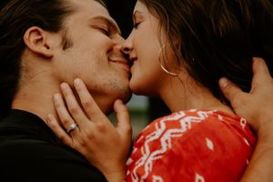 Couple sharing tender kisses during an outdoor photo session.