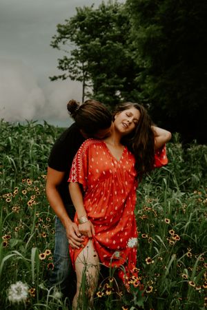 Couple posing playfully among wildflowers in a natural setting.