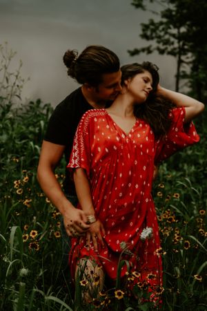 Couple sharing intimate moments in a field of orange wildflowers.