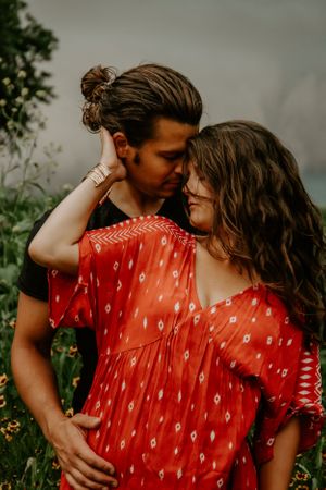A romantic outdoor photoshoot featuring a couple in red and dark clothing.