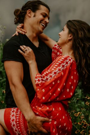 Couple sharing tender moments outdoors with woman in red patterned dress.