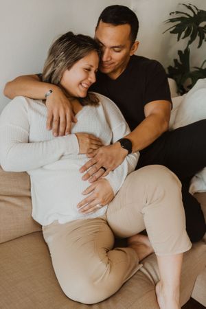Couple relaxing together on a beige couch in casual intimate moments.