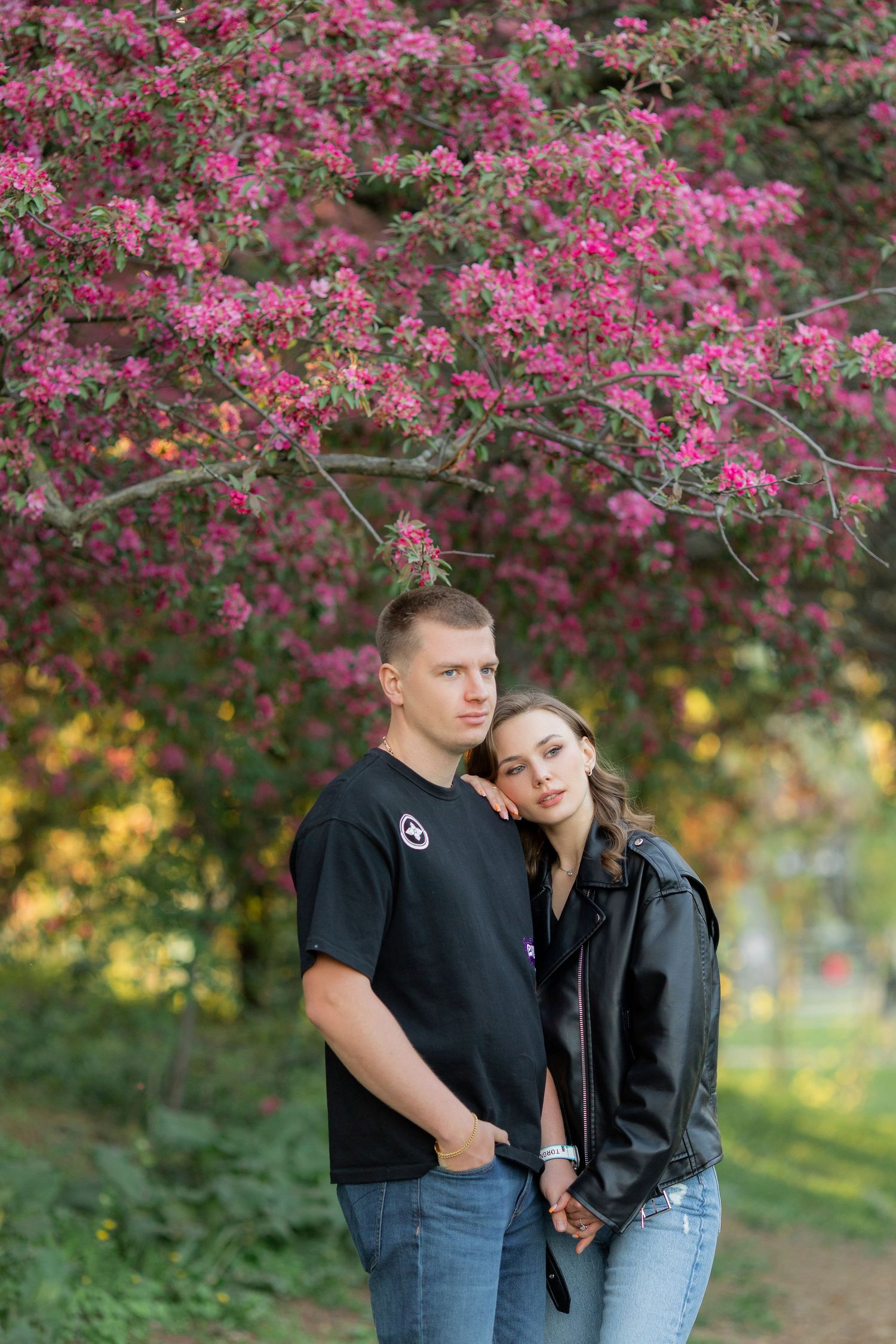 A romantic portrait under vibrant pink cherry blossoms with soft natural lighting.