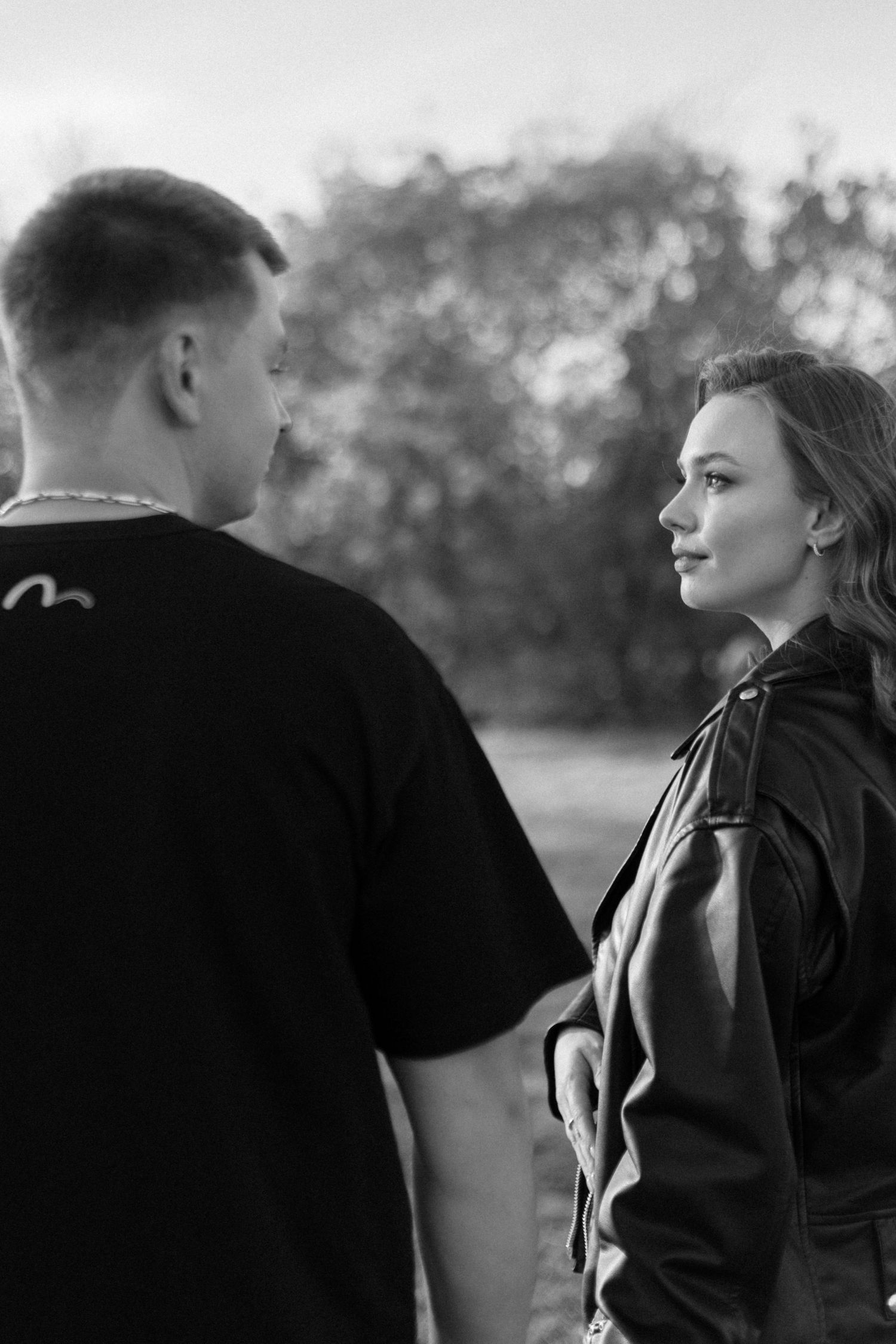 Two people share an intimate moment outdoors in black and white photography.