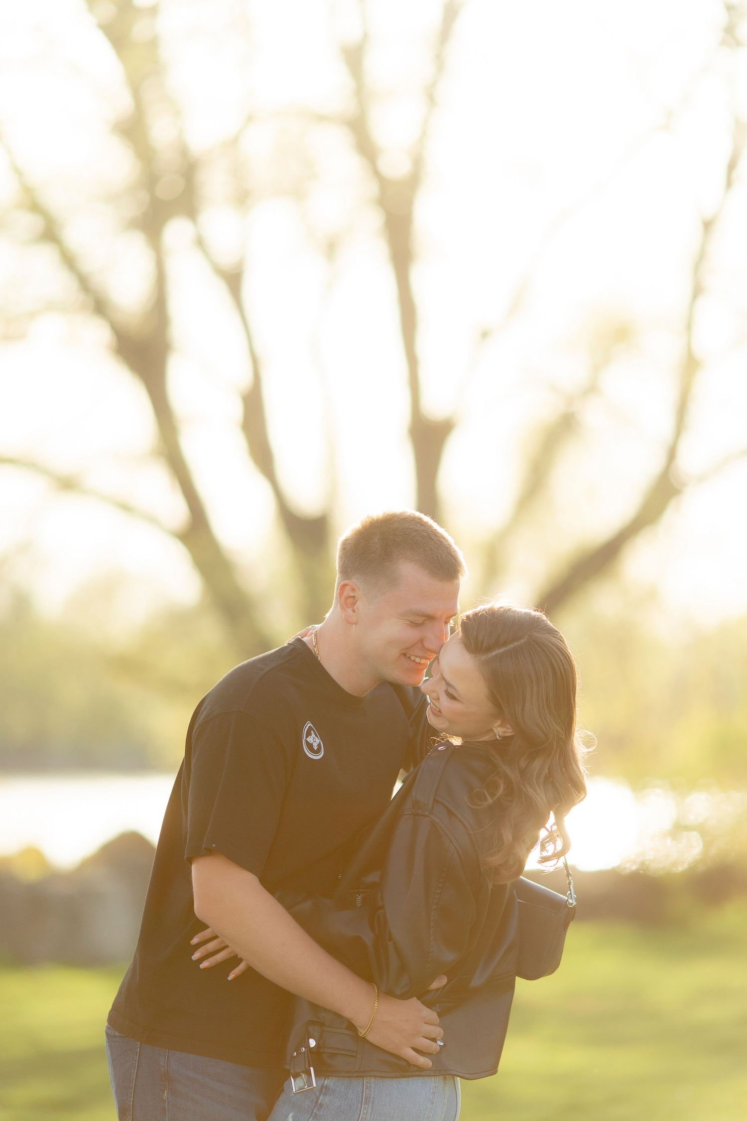 A couple shares a laugh while embracing in golden sunset light.