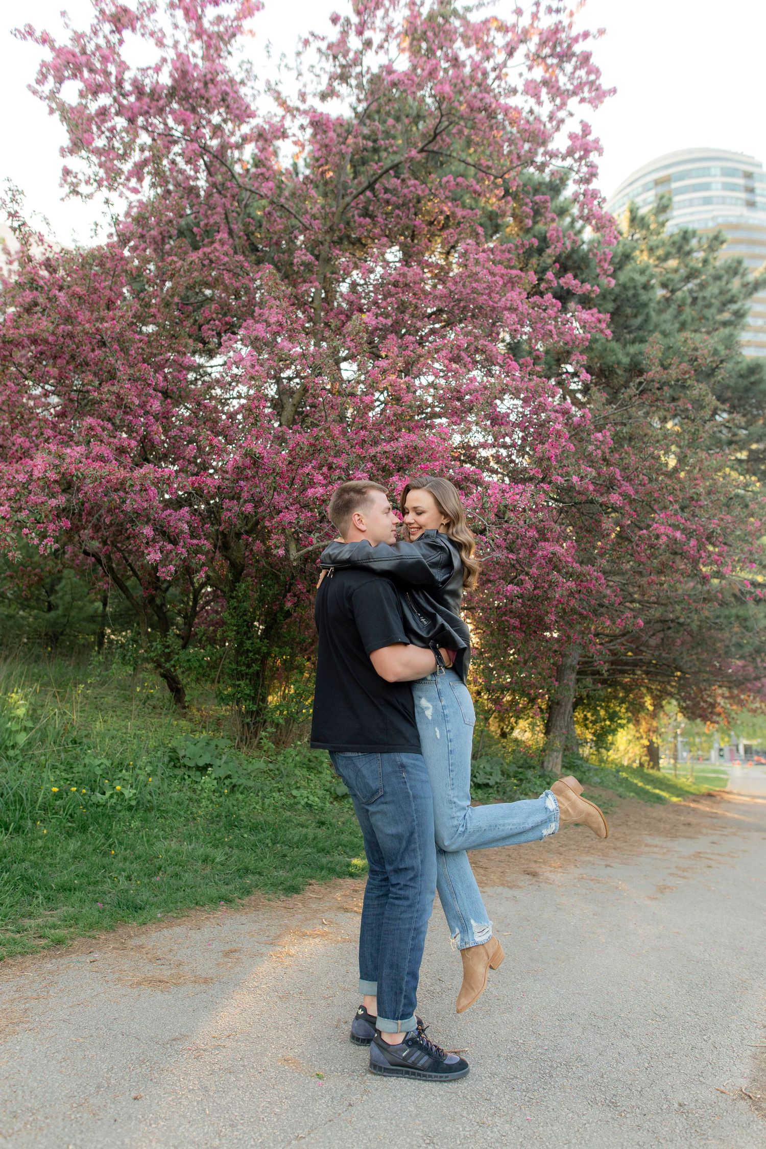 A romantic embrace under pink cherry blossoms on a spring afternoon.