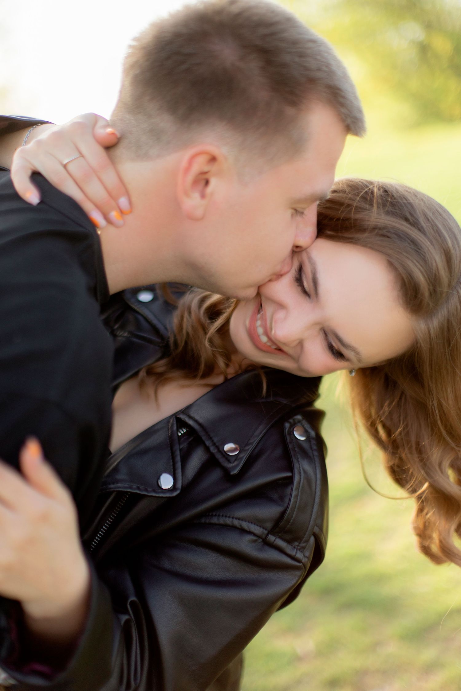 A tender moment shared between a couple wearing casual clothing outdoors.